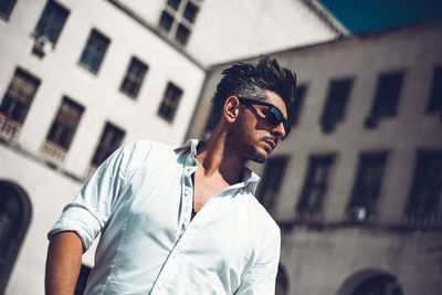 Man wearing sunglasses standing against built structure