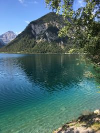 Scenic view of lake by mountains against blue sky