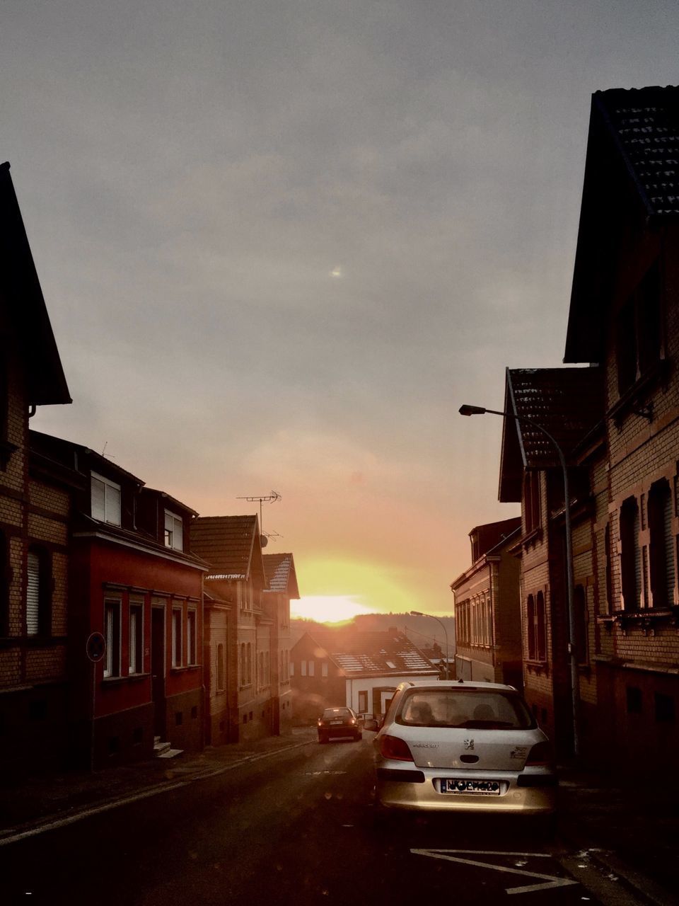 CARS ON STREET AMIDST BUILDINGS IN CITY AGAINST SKY