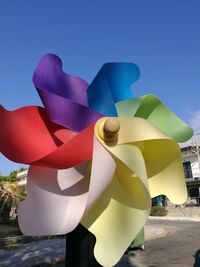 Close-up of multi colored umbrellas against blue sky