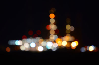 Defocused image of illuminated lights against sky at night