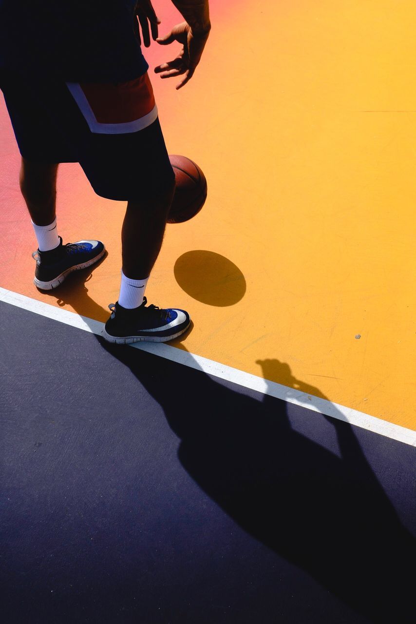 LOW SECTION OF MAN STANDING ON FLOOR AGAINST YELLOW WALL