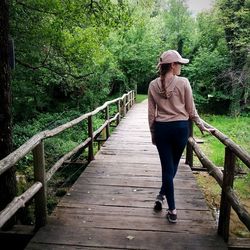 Full length of man standing on footbridge in forest