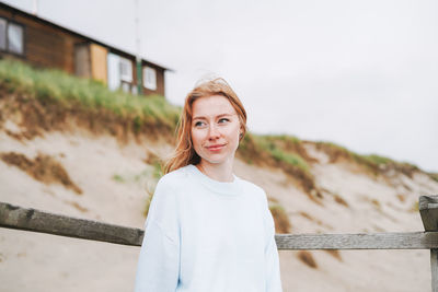 Portrait of young woman standing against building