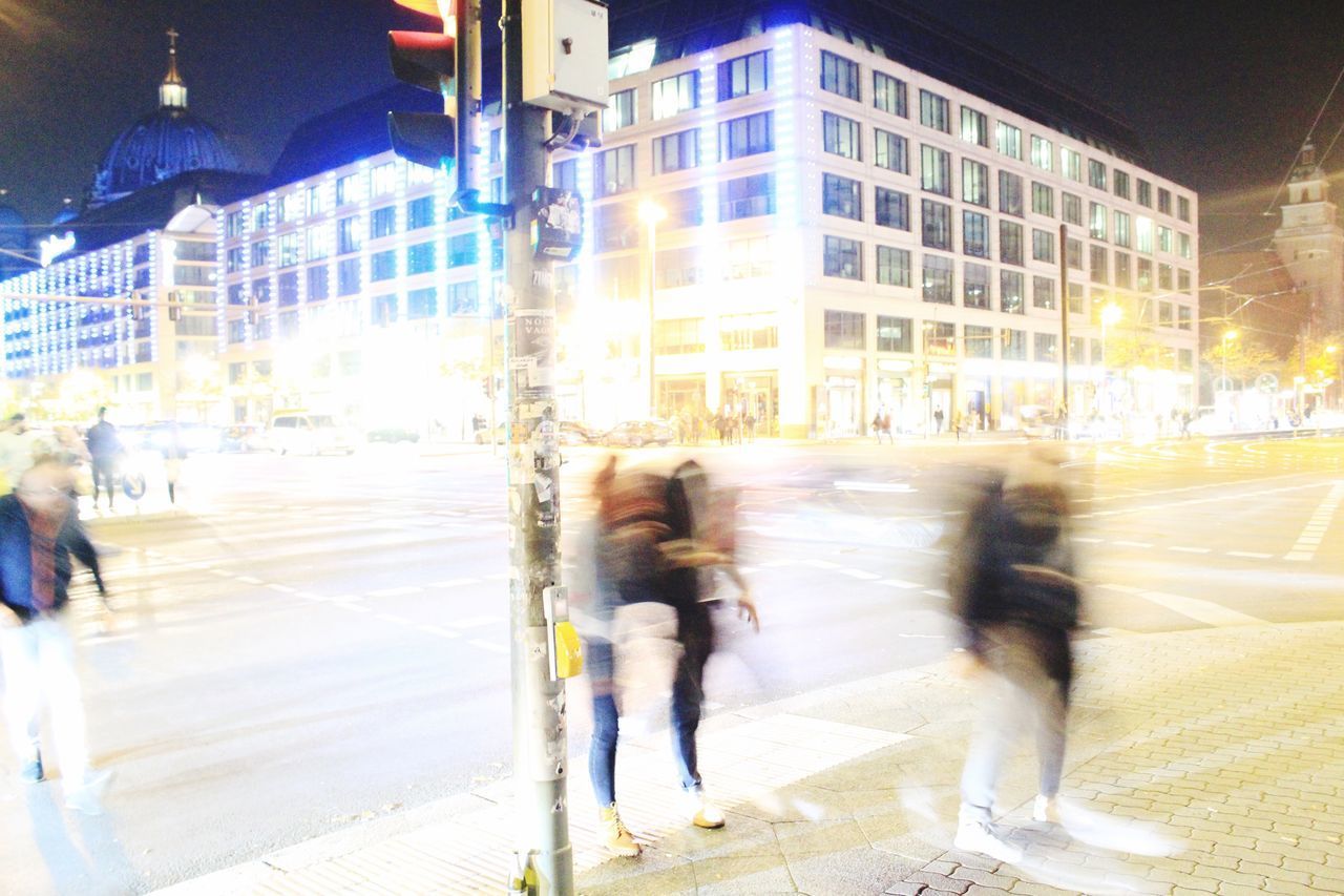 PEOPLE WALKING ON ROAD AMIDST BUILDINGS IN CITY