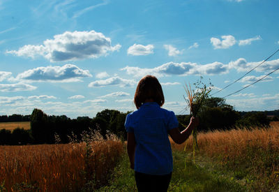 Rear view of woman standing on field against sky