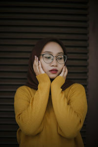 Young woman standing against corrugated iron