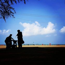 People on beach against cloudy sky