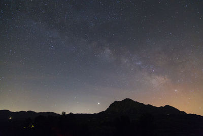 Low angle view of silhouette mountain against sky at night