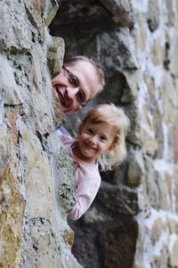 Portrait of father and daughter smiling amidst old wall