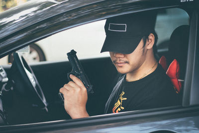 Man holding gun while sitting in car