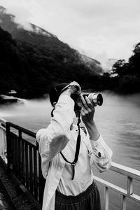 Rear view of woman photographing through binoculars