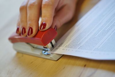 Close-up of woman stapling documents on table