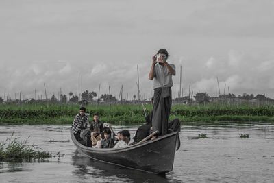 Man standing on boat in water against sky