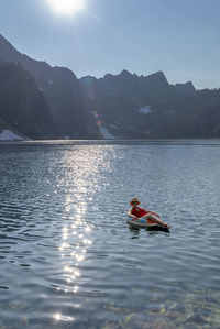 Woman on inflatable ring in lake against sky