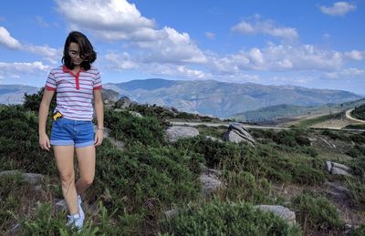 Teenage girl walking on field against sky