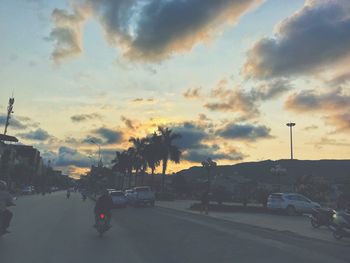 Cars on road against sky during sunset