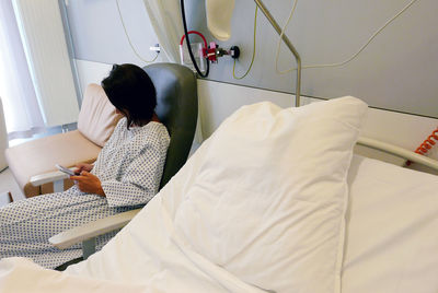High angle view of young woman using smart phone while sitting in hospital