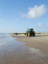 Bulldozer at beach against sky