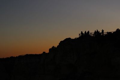 Silhouette people on landscape against clear sky during sunset