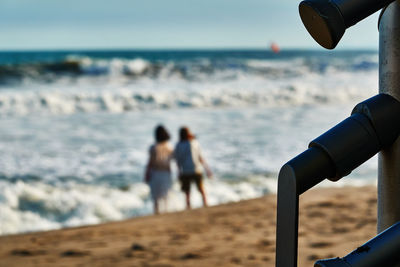 Rear view of women standing at beach