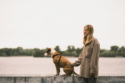 Side view of woman with dog against sky