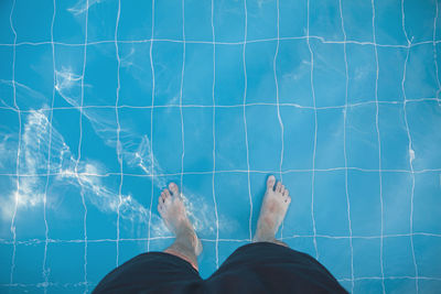 Low section of man standing in swimming pool