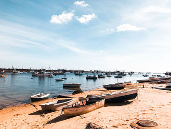 Boats moored at harbor against sky