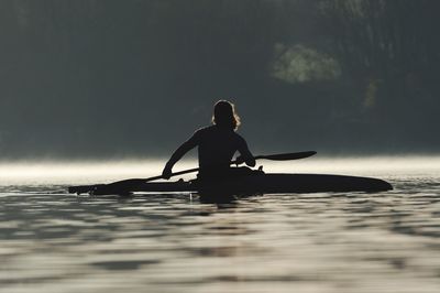 Silhouette man on boat in sea against sky