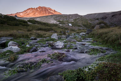 Scenic view of stream flowing through rocks against sky