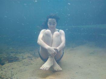 Teenage girl with eyes closed swimming undersea