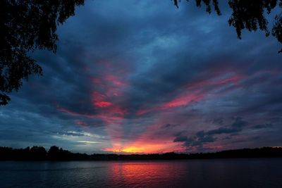 Scenic view of lake against dramatic sky during sunset