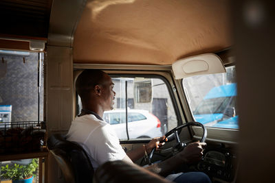 Side view of mid adult man driving food truck in city