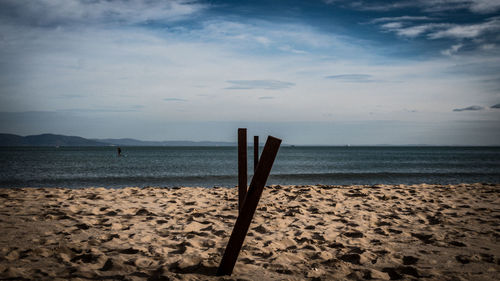 Wooden posts on beach against sky