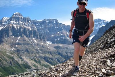 Man wearing sunglasses on rock against sky