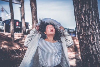 Mid adult woman standing against tree trunk