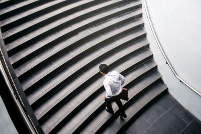 High angle view of man with bag walking on staircase