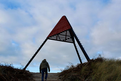 Rear view of man standing on field against sky