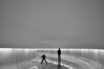 People walking on illuminated road against clear sky