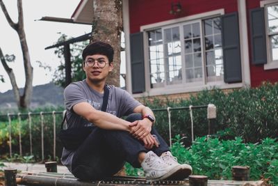 Young man sitting in yard against building