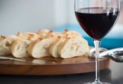 Close-up of wineglass by breads on table