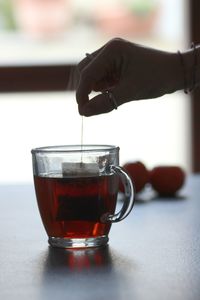 Close-up of hand pouring tea in glass