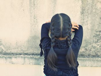 Rear view of woman standing against wall