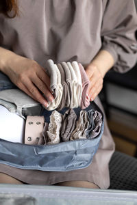 Midsection of woman holding clothes at home