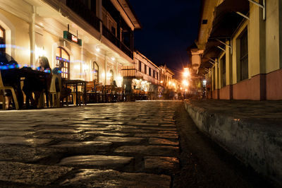 Illuminated street amidst buildings at night