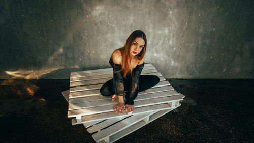 Portrait of young woman standing by wall