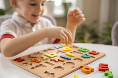 Midsection of boy playing with toy blocks on table