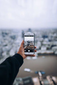 Midsection of man using mobile phone against sky