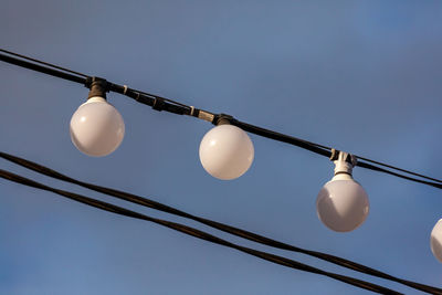 Low angle view of light bulbs against sky