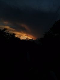 Silhouette trees against dramatic sky during sunset